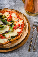 Neapolitan Margherita pizza with tomatoes, mozzarella, basil and olives on stone table
