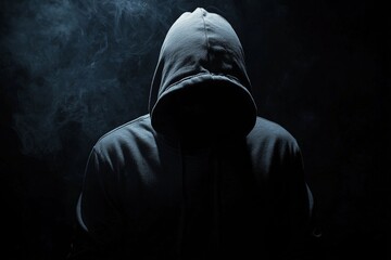 A hooded figure shrouded in darkness is surrounded by swirling smoke, creating an intense and foreboding atmosphere that suggests mystery and anonymity.