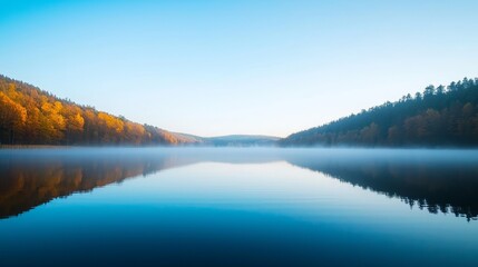 Fototapeta premium Serene lake with misty morning fog reflecting trees and hills. Peaceful landscape.