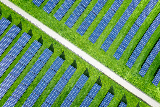 Overhead view from a drone over of a large array of solar panels on a solar farm with rows of modern photovoltaic solar panels in a green agricultural field. Agrivoltaics concept in Spain