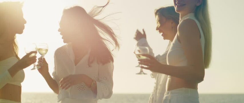 Candid conversation among friends by the sea, the light reflecting beautifully off the water as they enjoy their drinks.