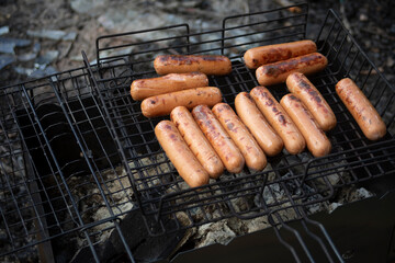 Sausages on a picnic. Roasting meat on coals. Cooking food on fire.