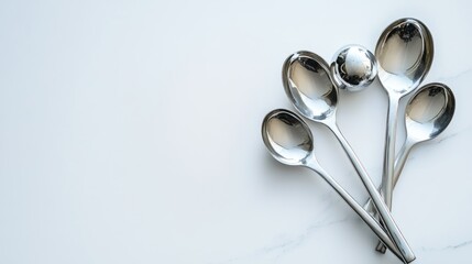 A collection of silver spoons arranged on a marble surface.