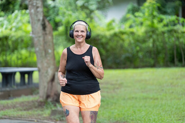 Elderly woman smiling while jogging in park