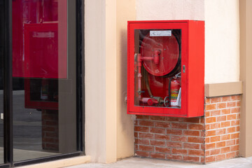 A red fire hydrant is mounted on a brick wall