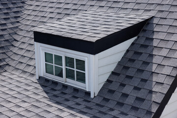 A roof with a garret window and roof shingle.