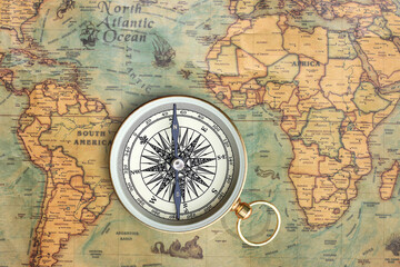 Classic round compass on background of old vintage map of world