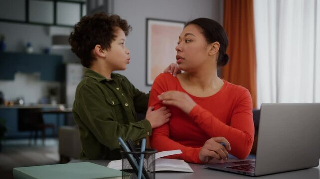 African American family upset tired multitasking mother woman female freelancer girl business task write working home laptop little child kid son sad boy come in ask need attention mom say no ignore