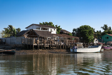 Obraz premium A tranquil village along the riverbank in Morondava, Madagascar showcasing traditional wooden houses and fishing boats
