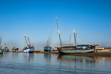 Fototapeta premium Traditional fishing boats lined along the riverbank in Morondava, Madagascar during a sunny day