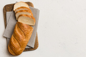 Freshly baked bread slices on cutting board against white wooden background. top view Sliced bread