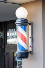 There is a red, white, and blue barber pole attached to the buildings side