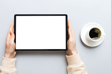 Close up image woman hands holding digital tablet with blank copy space screen for your text message or promotional content om table with cup of coffee. hands of a woman holding blank tablet device