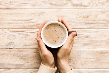Minimalistic style woman hand holding a cup of coffee on Colored background. Flat lay, top view...