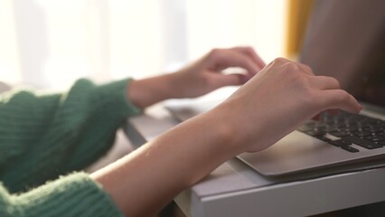 Girl with her hands typing on laptop. lifestyle woman work from home. concept. hands of a woman typing on a. laptop. a girl with large hands typing on a laptop.