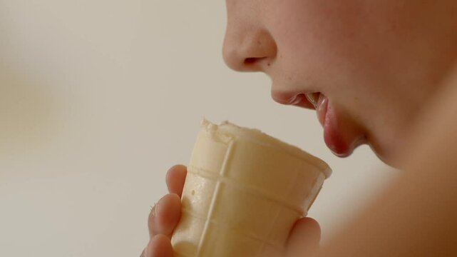A brighteyed child joyfully savors a delicious ice cream cone, encapsulating all those delightful summer moments lick vanilla ice cream with tongue, teen mouth close up