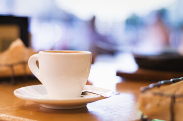 A cup of coffee in a saucer in a cafe on a blurred background. The concept of coziness and comfort