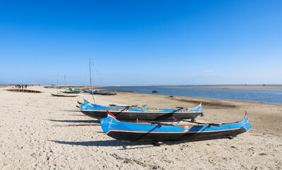 Fototapeta premium Beach activity along the coastline of Madagascar featuring traditional fishing boats under a clear blue sky
