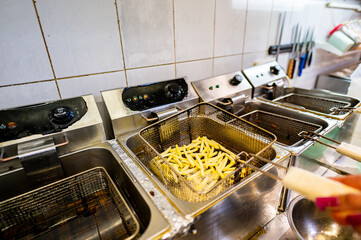 Close-up of a commercial deep fryer with French fries being cooked, highlighting the concept of...