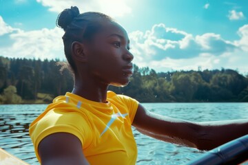 Fototapeta premium A young rower in a yellow shirt glides across a sunny lake, showcasing concentration and resolve.