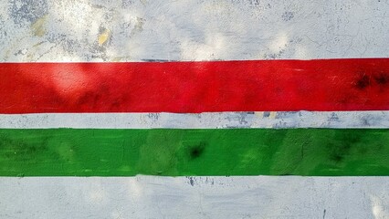 A green and red striped wall with a white stripe The wall is covered in graffiti.