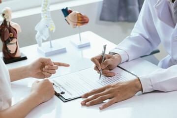 Asian male doctor consults with patient in clinic, reviews medical documents and uses stethoscope to diagnose health conditions, and confidently provides professional advice and care.