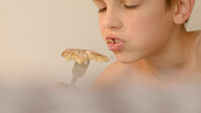 he puts food in his mouth with a pitchfork and chews at breakfast child finds joy in savoring delicious food, capturing childhood innocence and creating lasting mealtime memories 