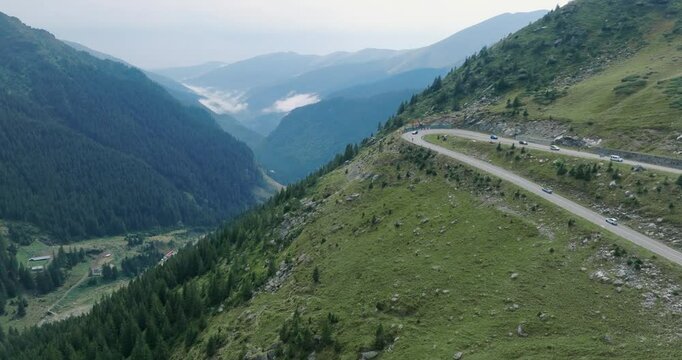 Aeriel Drone View of the Transfagarasan Highway in the Carpathian Mountains of Transylvania in summer with green forest and grass. Winding Road with cars driving in 4K