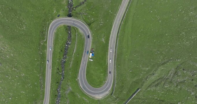 Top Down Aeriel Drone View of the Transfagarasan Highway in the Carpathian Mountains of Transylvania in summer with green grass. Winding Road with cars driving in 4K