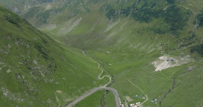 Aeriel Drone View of the Transfagarasan Highway in the Carpathian Mountains of Transylvania in summer with green forest and grass. Winding Road with cars driving in 4K
