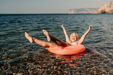 A woman is in the ocean on a red raft