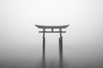 Selbstklebende Fototapeten Minimalist black and white photograph of a torii gate reflecting on tranquil water in a serene and misty atmosphere © Georgii