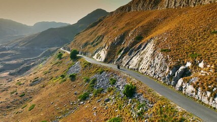 Fast sports motorcycle rides on mountain road with serpentines. Traveling together on motorbike concept. Summer adventure in the mountains. Aerial drone shot