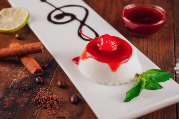 White plate with a dessert, a cherry, and chocolate sauce