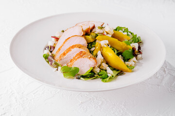 Grilled chicken breast salad with yellow bell peppers and feta cheese on white plate