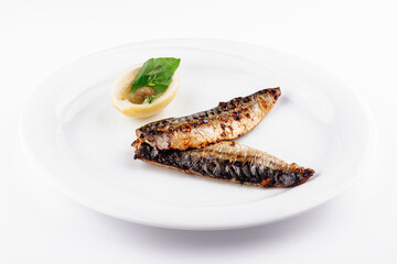 Grilled mackerel fillets served on white plate with lemon and basil garnish
