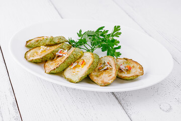 Grilled zucchini slices with herbs and spices on white plate