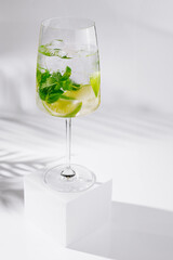 Refreshing summer cocktail with lime and mint standing on white cube