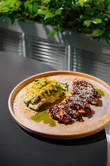 Grilled teriyaki chicken breast with white sesame seeds served with green salad on elegant restaurant table