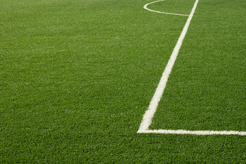 Artificial green grass with white stripe of soccer field. Outdoors. Summer. Close up.