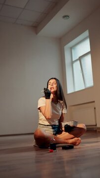 Young woman eating sushi burger with chopsticks while sitting in lotus position. Japanese food concept. Sushi burger in hands.Vertical vedeo 4K