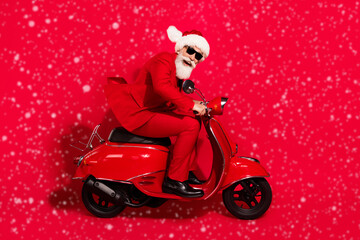 Photo of charming funky mature motorcyclist dressed christmas costume hat smiling hurrying isolated red color background