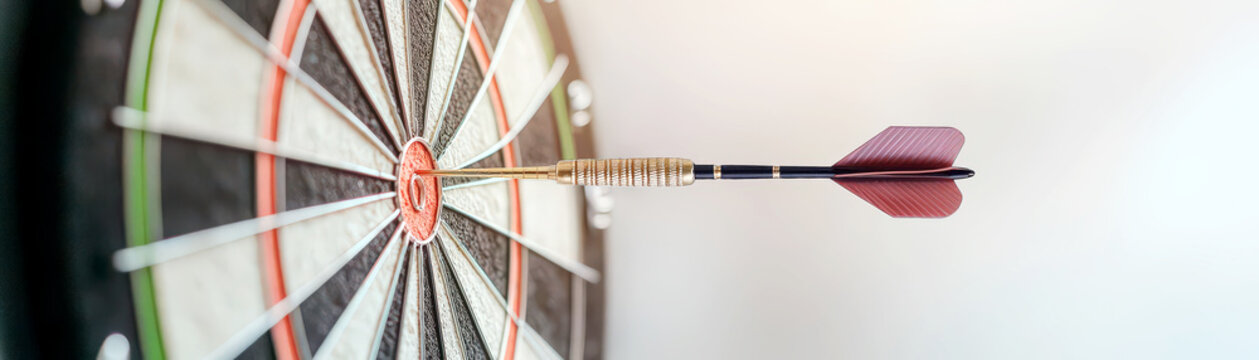 A person carefully aiming a dart at a dartboard, symbolic of pre