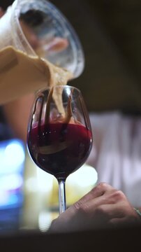 Closeup angled vertical undershot of sweet cocktail drink being prepared at hotel bar, with chocolate, cream and berries cherry filling underneath. Shot on 1080p at 100fps.
