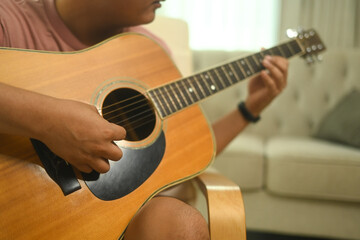 Obraz premium Cropped image of man playing an acoustic guitar in a cozy living room