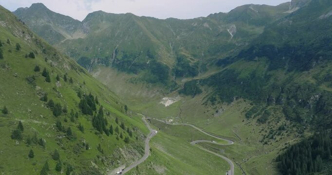 Aeriel Drone View of the Transfagarasan Highway in the Carpathian Mountains of Transylvania in summer with green forest and grass. Winding Road with cars driving in 4K