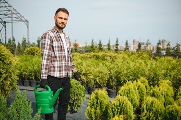 Male employee of garden shopping center inspects product. Department with potted plants, is...