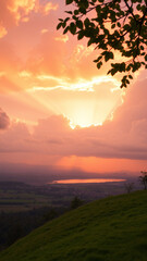 Fototapeta premium Tranquil sunset scene, glowing clouds and sunrays over quiet countryside, distant town, serene lake, green fields, and a grassy hill with trees. Perfect for relaxation.