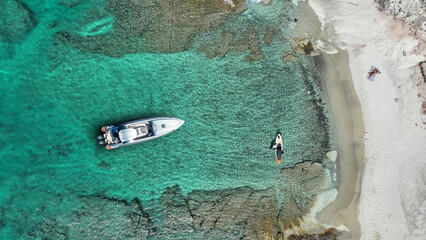 Aerial drone top down photo with copy space of inflatable rib speed boat anchored in tropical exotic rocky island with emerald crystal clear sea