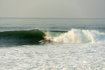 Surfer riding a wave at sunrise in the ocean
